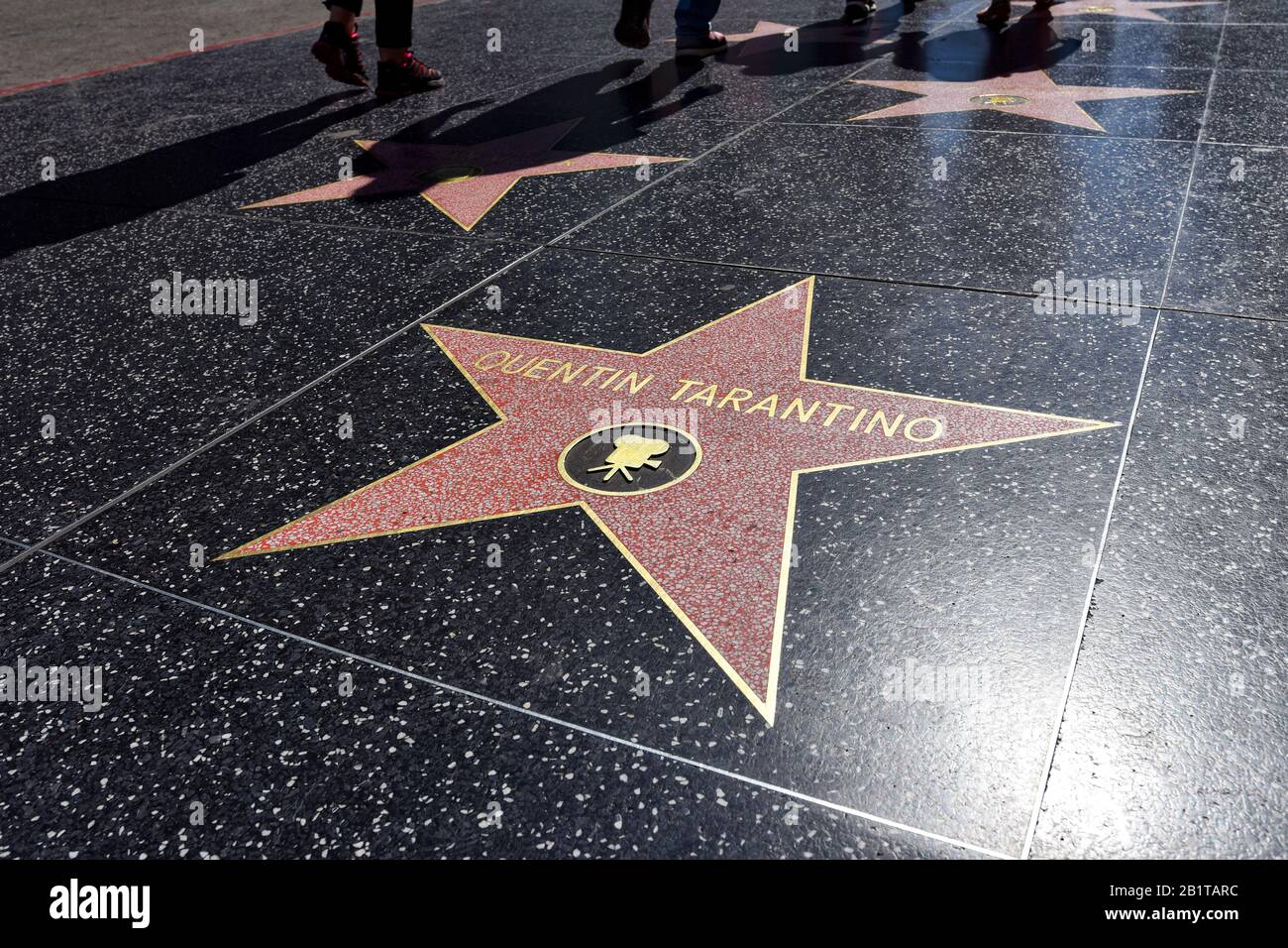 Der Stern von Quentin TARANTINO, eingebettet in den Terrazzo-Dielen des Hollywood Boulevard Walk of Fame mit Schatten von Touristen im Hintergrund. Stockfoto