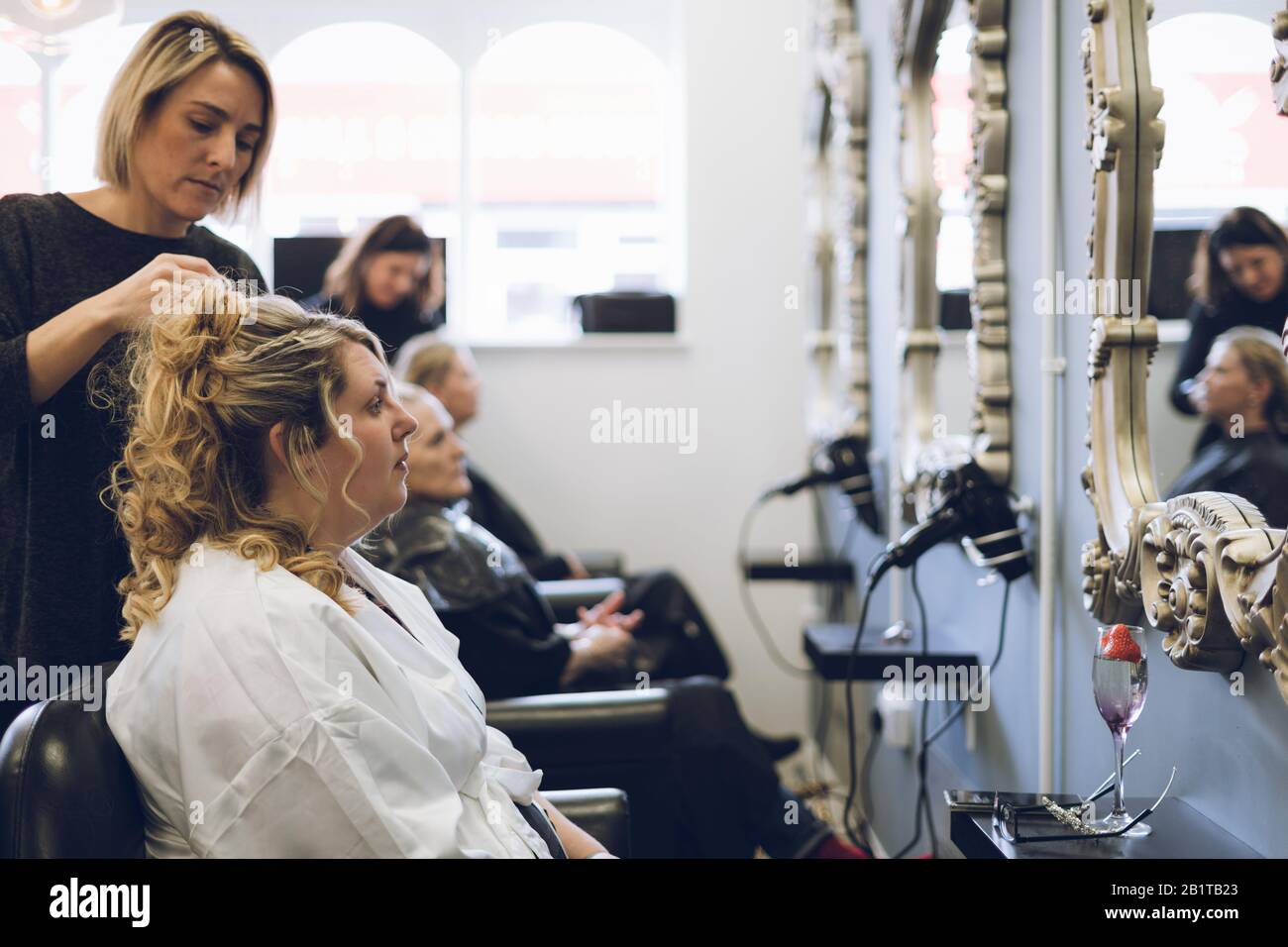 Frauen, die vor einem Spiegel Haare am Friseursalon oder im Friseursalon gestylt haben Stockfoto