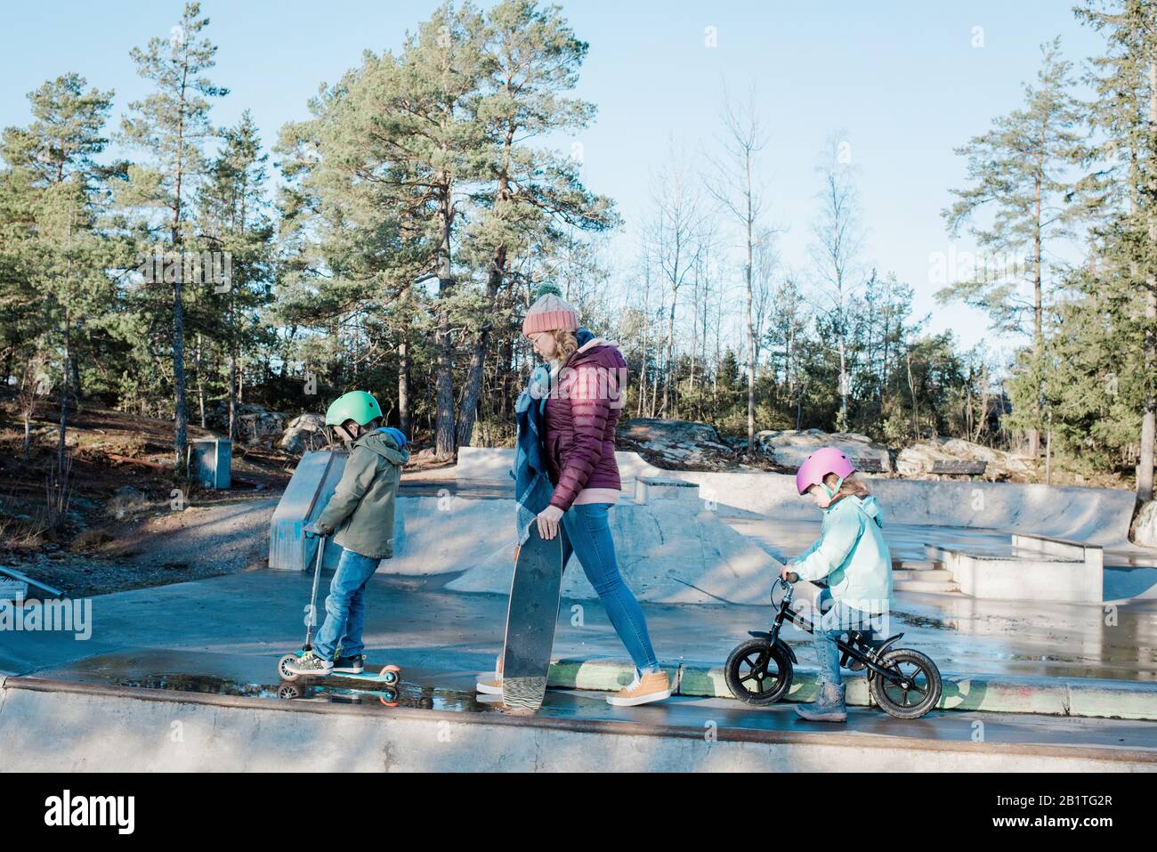 Mama und ihre Kinder laufen über einen Skatepark, um zu reiten und Spaß zu haben Stockfoto