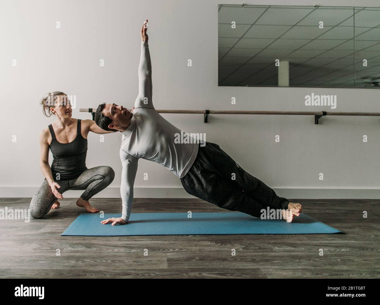 Weibliche Personal Trainer trainiert männlichen Kunden tun eine seitwärts Plank Stockfoto