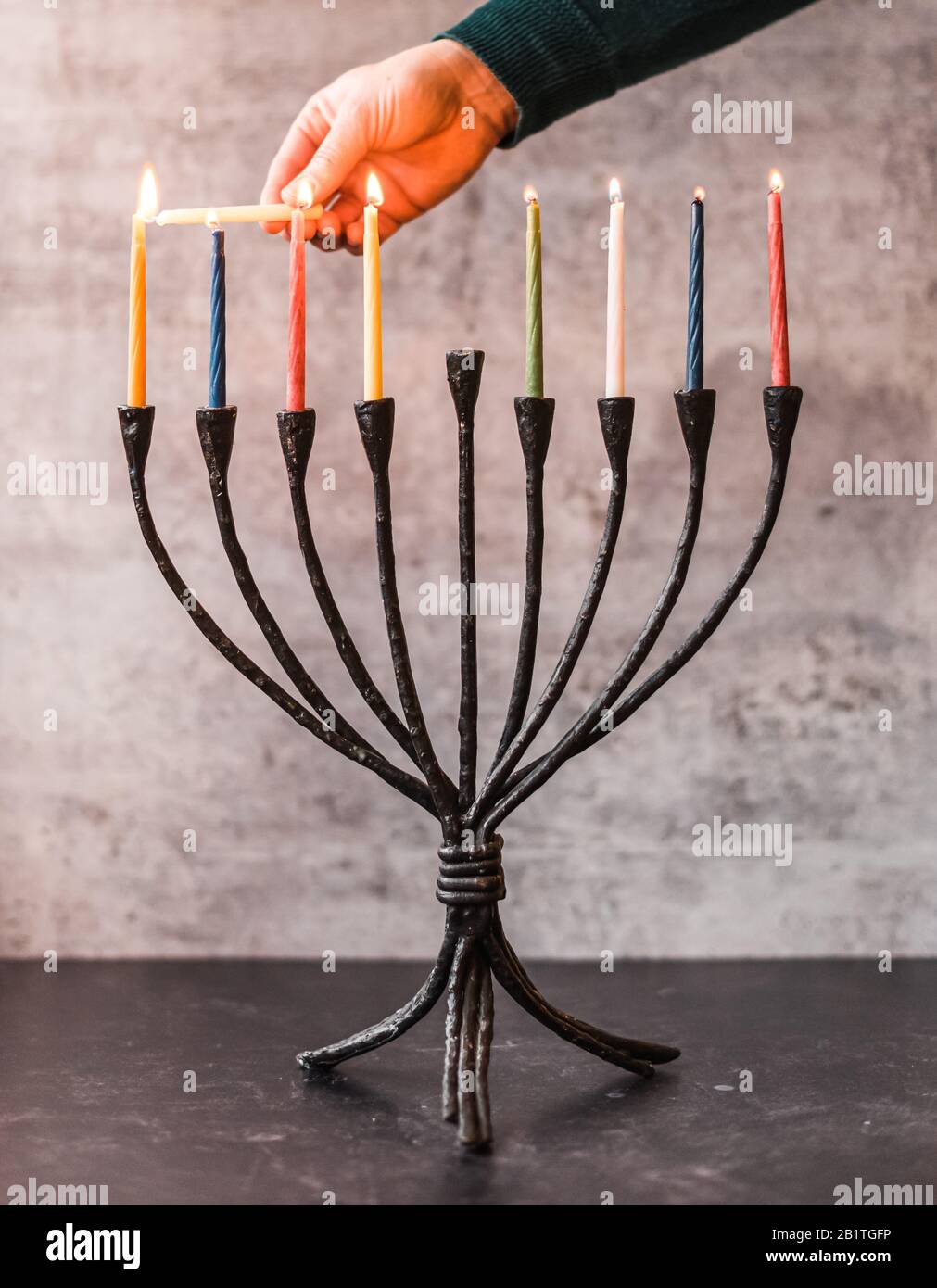 Bild einer Hand, die Kerzen auf Menorah für Chanukka anzündet. Stockfoto