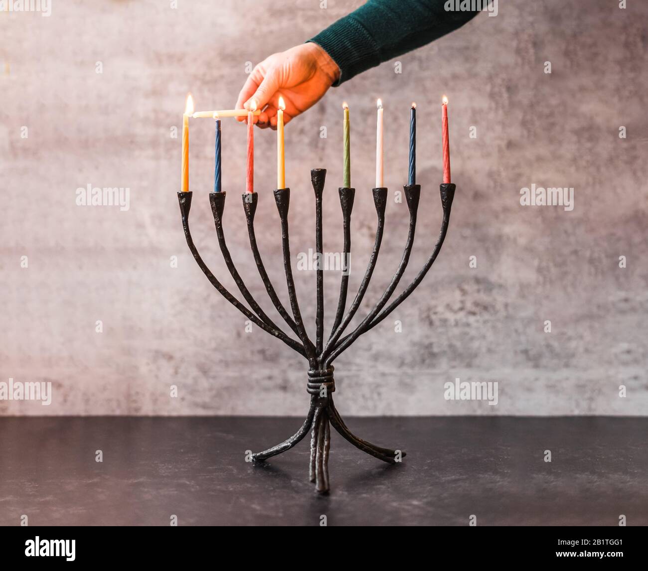 Bild einer Hand, die Kerzen auf Menorah für Chanukka anzündet. Stockfoto