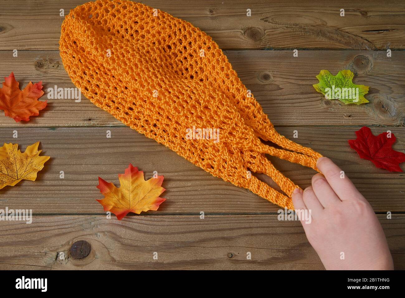 Orangefarbene Saite auf Holzhintergrund mit herbstlichen Blättern. Kein Abfall-Shoppingkonzept. Stockfoto