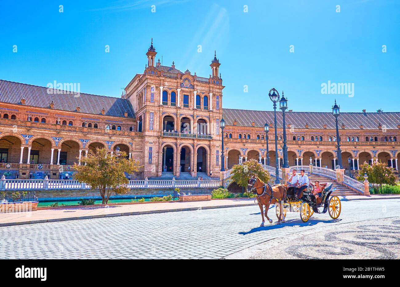 Sevilla, SPANIEN - 1. OKTOBER 2019: Die Pferdekutsche fährt um die große Plaza de Espana entlang eines prächtigen halbrunden Gebäudes mit Bogenba Stockfoto