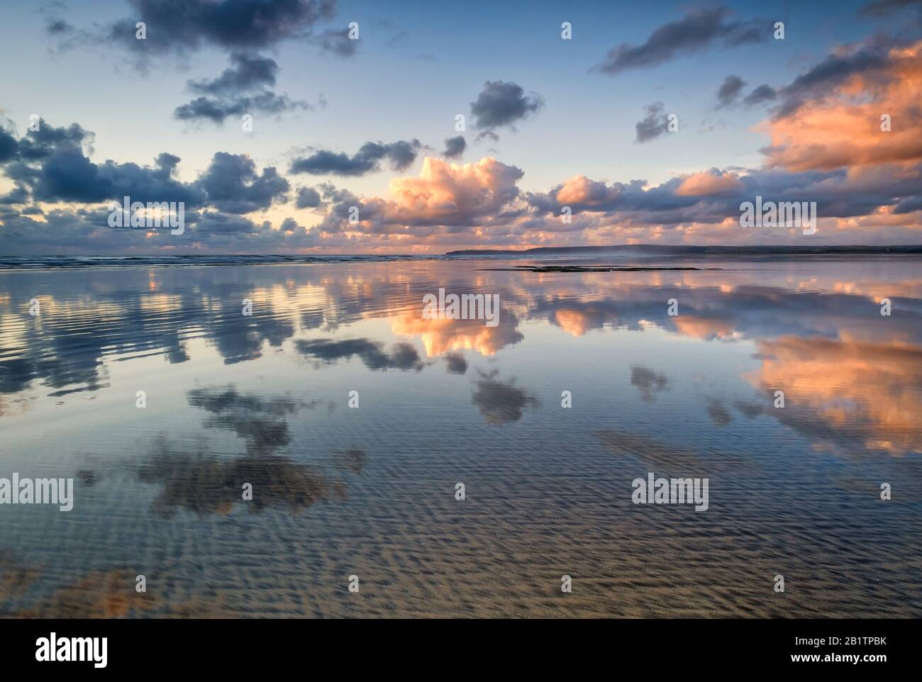 Spiegelbild des Sonnenuntergangs und der Wolken, die sich auf dem nassen Sand des Strandes spiegeln, Küstenleben, dramatischer Himmel, Reflexionen, Sand, atmosphärisch Stockfoto