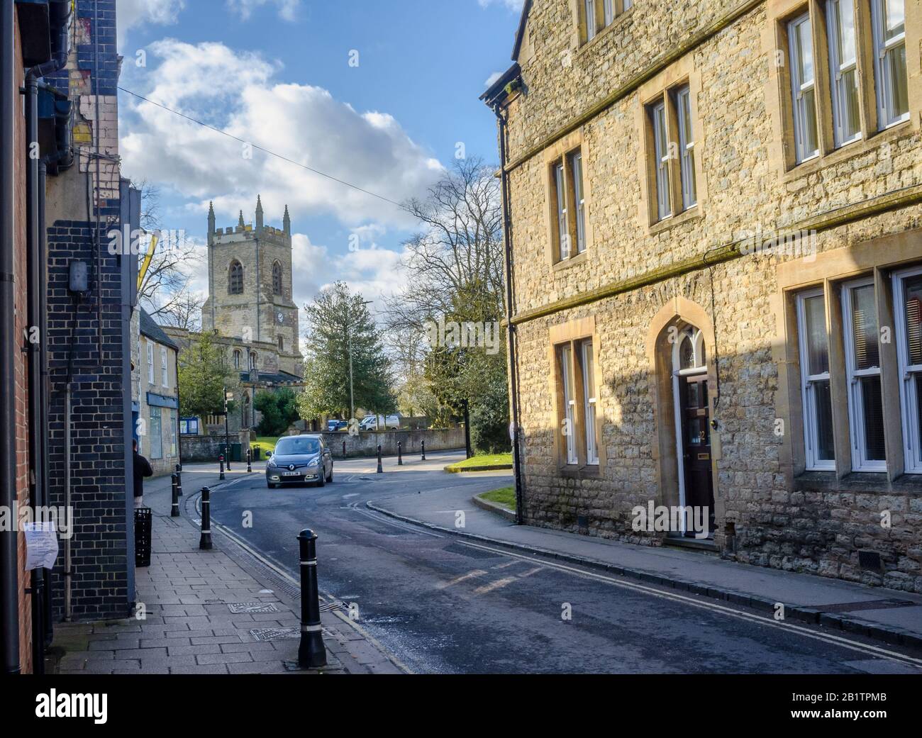 ST Edburgs Church an der Kreuzung von Church Street und Causeway, Bicester, Oxfordshire, Großbritannien. An einem sonnigen Tag, im Spätwinter, gedreht. Blaues Auto mitten auf der Straße. Stockfoto