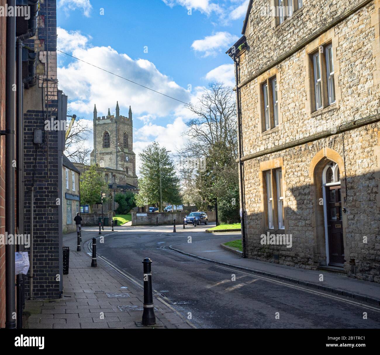 ST Edburgs Kirche, an der Kreuzung von Church Street und Causeway, Bicester, Oxfordshire, Großbritannien, Wurde An einem sonnigen Tag, im späten Winter, Erschossen. Blaues Auto nähert sich. Stockfoto