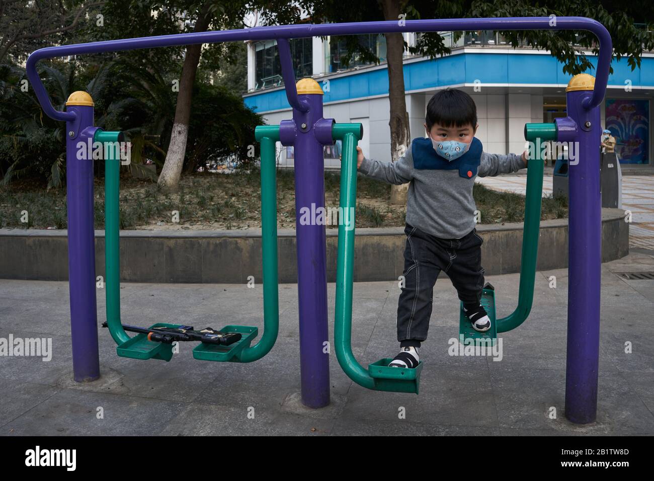 Ein Kind, das den Wanderer in einem Freizeitpark mit einer chirurgischen Maske verwendet, um die andauernde Coronavirus-Krankheit zu verhindern. Stockfoto