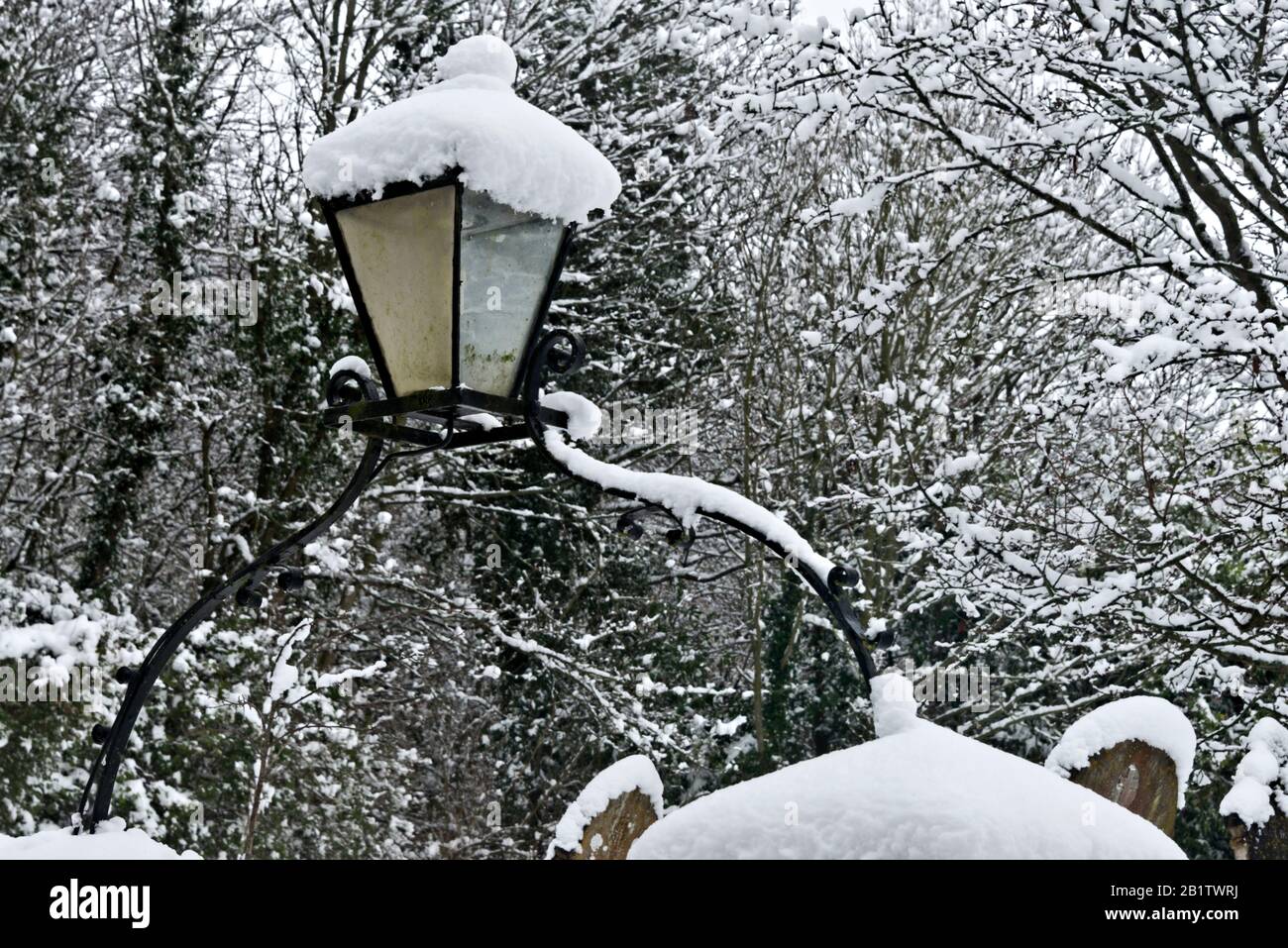 Eine Lampe über dem Tor der 13c-Dorfkirche St Mary in Stoke St Mary bei Taunton, Somerset, England, Großbritannien, nach einem starken Schneefall. Stockfoto