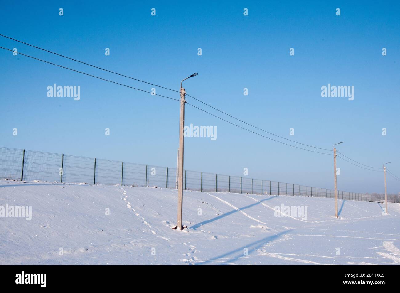 Vor dem Hintergrund einer Winterlandschaft elektrischer Pol von Stromleitungen und Drähten mit blauem Himmel Stockfoto