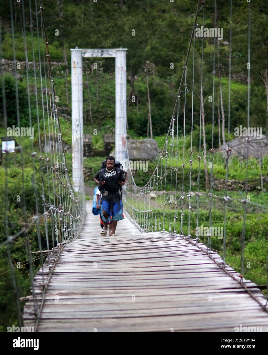 Trekking Porter, der auf Hängebrücke, Baliem Valley, Occidental Papua, Indonesien läuft Stockfoto