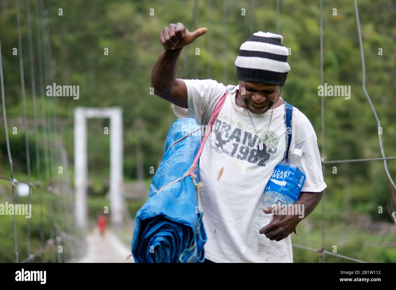 Trekking Porter, der auf Hängebrücke, Baliem Valley, Occidental Papua, Indonesien läuft Stockfoto