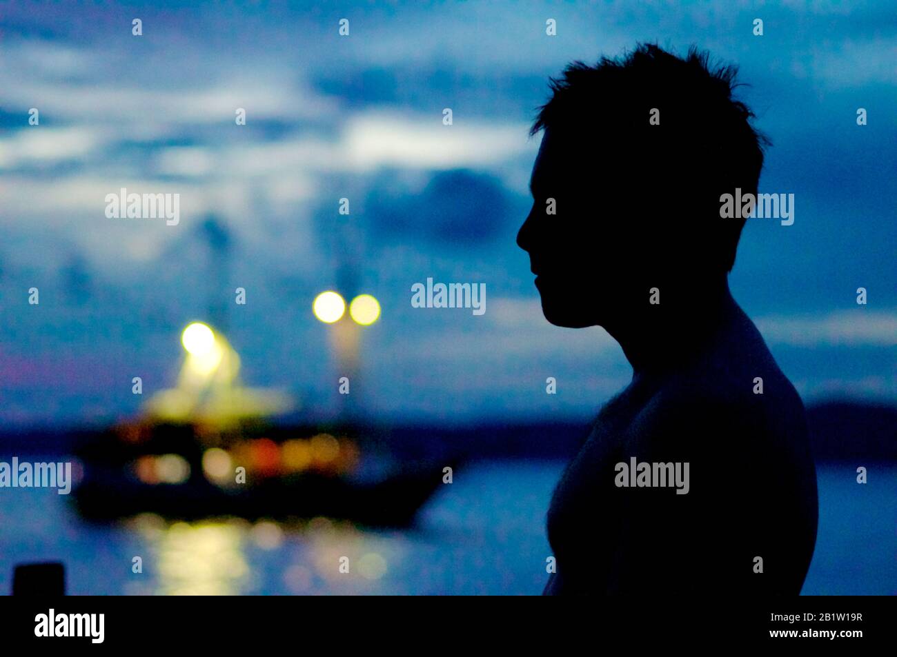 Man Silhouette in der Dämmerung mit Segelboot, nach Sonnenuntergang auf den Raja Ampat Inseln - Occidental Papua Stockfoto