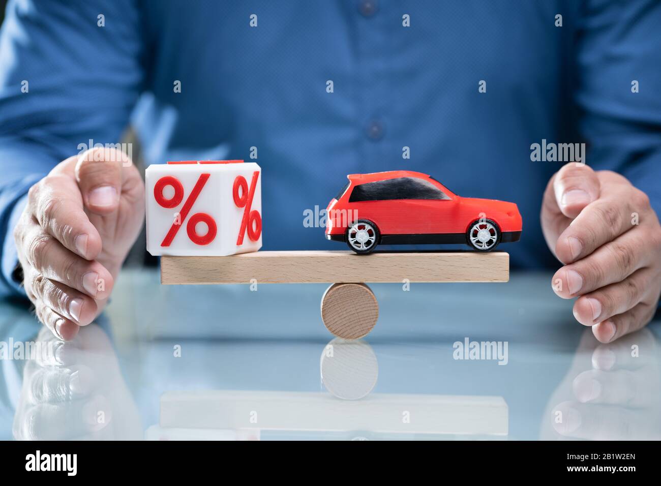 Der Unternehmer schützende Hand Balance zwischen Kubische Block mit Prozentzeichen und blaues Auto Stockfoto