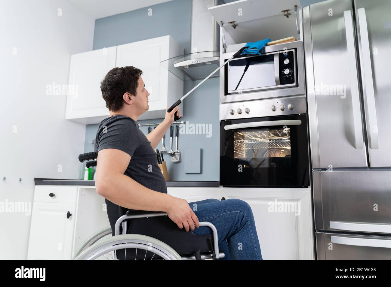 Behinderter Mann Mit Grabber Tool Zum Grabbeln Von Potholdern In Der Küche Stockfoto