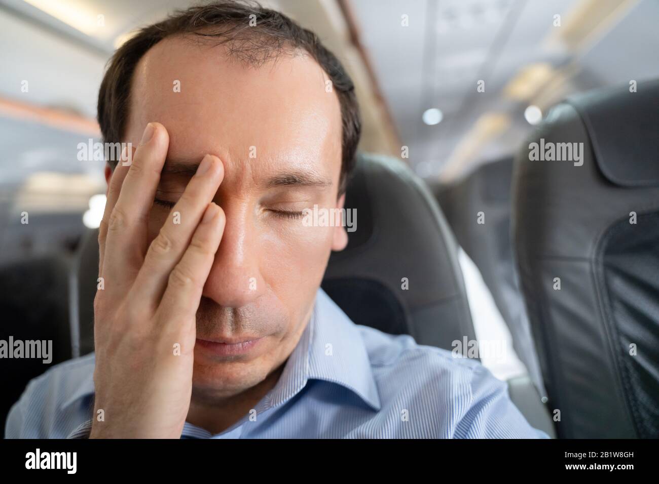 Junger Mann, Der An Einer Luftkrankheit Im Flugzeug Leidet Stockfoto