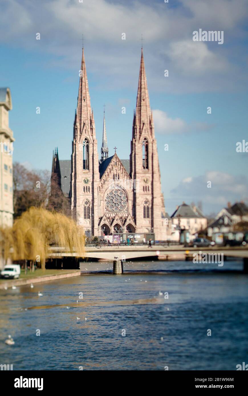 Straßburg, Frankreich - 20. Februar 2013: Blick auf die Straßburger St. Pauls Kirche das große Gebäude der Gotik im Stil der Architektur mit Einem Unübertrumten Fluss und einer Brücke mit Straßenbahnstation Stockfoto