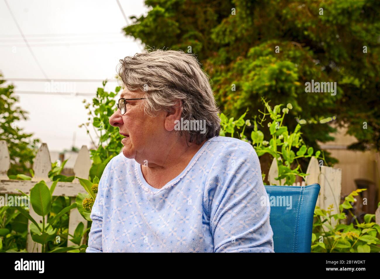 Frau mit ernsthaftem Ausdruck hört auf Sohn, während sie in ihrem Hinterhof in Ludington, Michigan, USA sitzt. Stockfoto