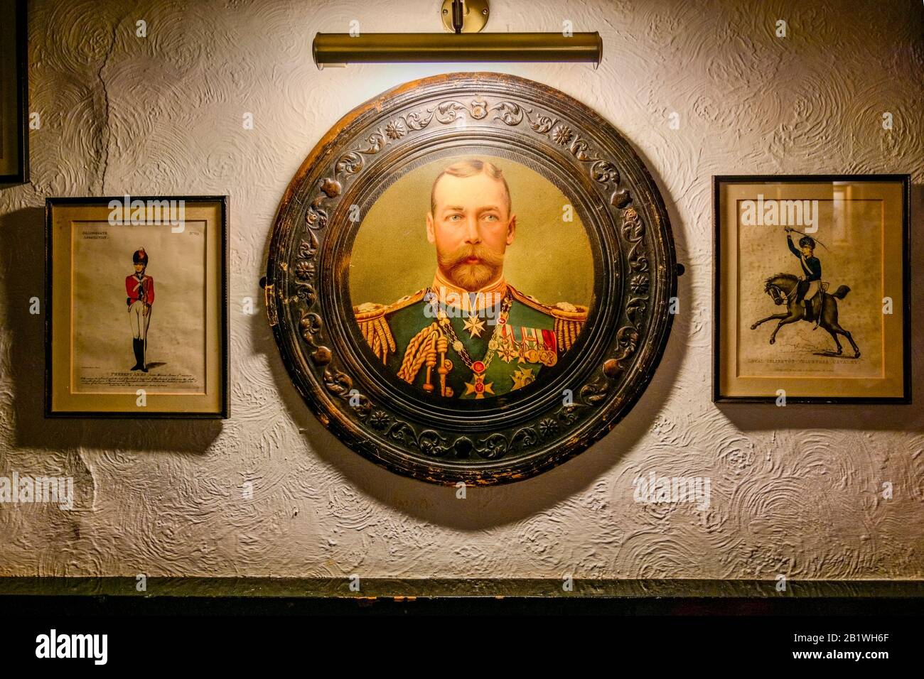 Druck des ersten offiziellen Porträts König Georg V. an der Kneipwand im runden Rahmen. Stockfoto