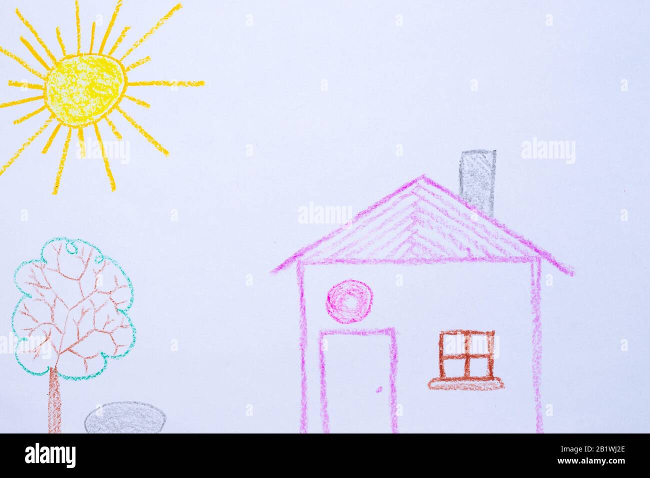 Kinderzeichnung von Haus, Baum, Sonne und Felsen auf weißem Papier