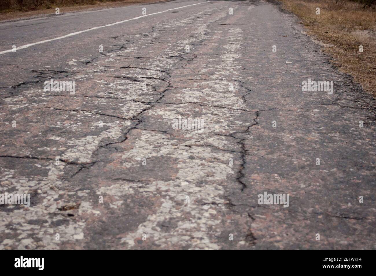 Foto einer schlechten Straße, zerstörte graue Asphalt, in der Nähe Stockfoto