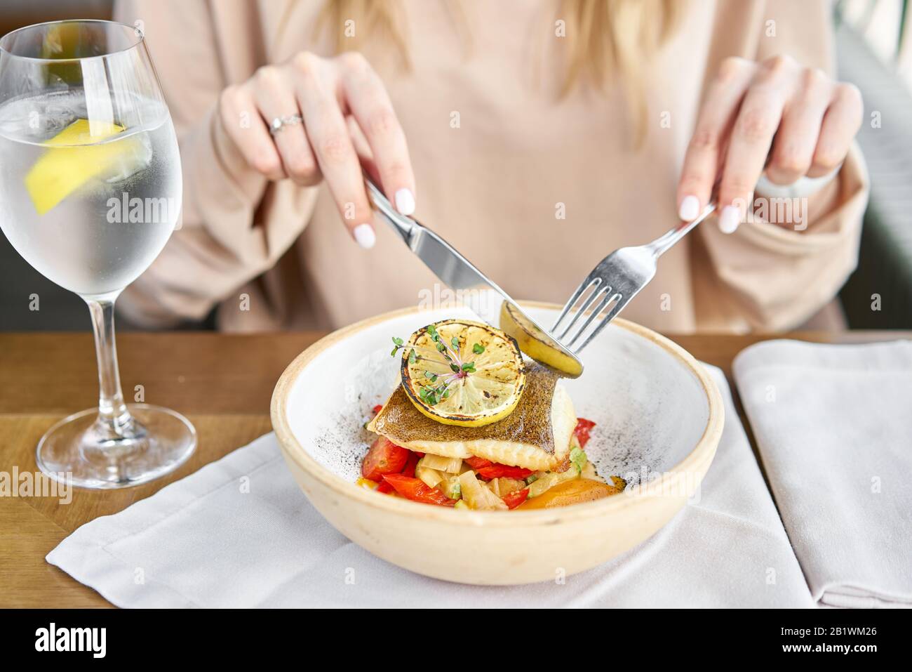 Gebratener Heilbutt mit Gemüse, Paprika Pfeffer und Kürbis Creme. Mittagessen im Restaurant, eine Frau isst Lecker und gesund Essen. Schale mit eingerichtet Stockfoto