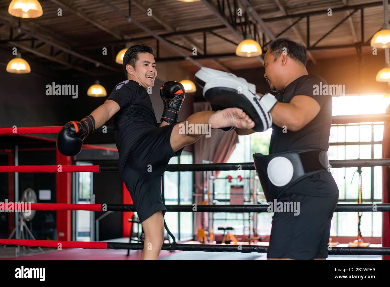 Asiatischer Kickboxer tritt Profi-Trainer im Boxstuduim im Hintergrund im Fitness-Fitnessstudio an. Boxer trainieren für Körperbau und gesundes li Stockfoto