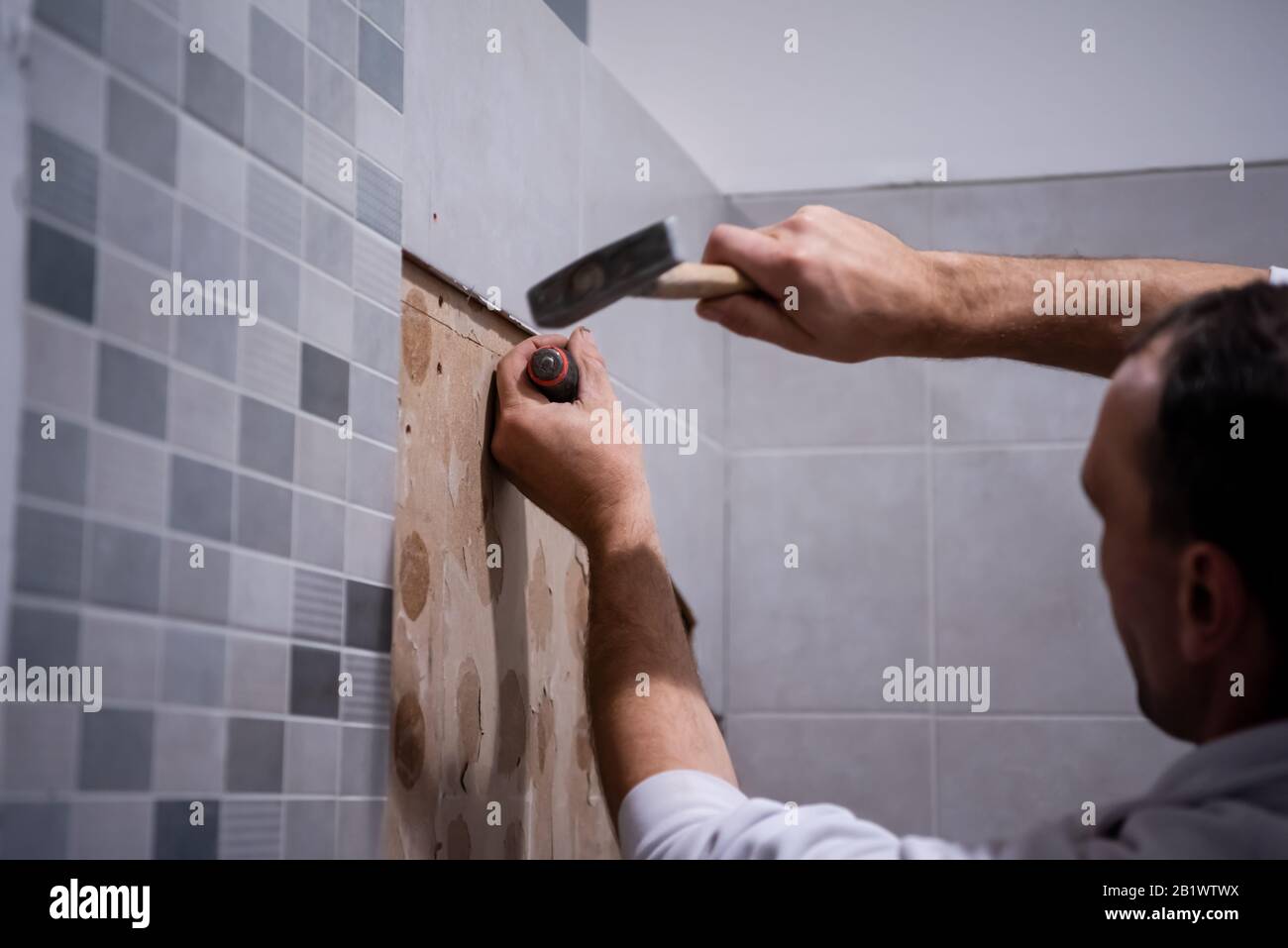 Facharbeiter entfernen in einem Badezimmer mit Hammer und Meißel alte  Fliesen Stockfotografie - Alamy