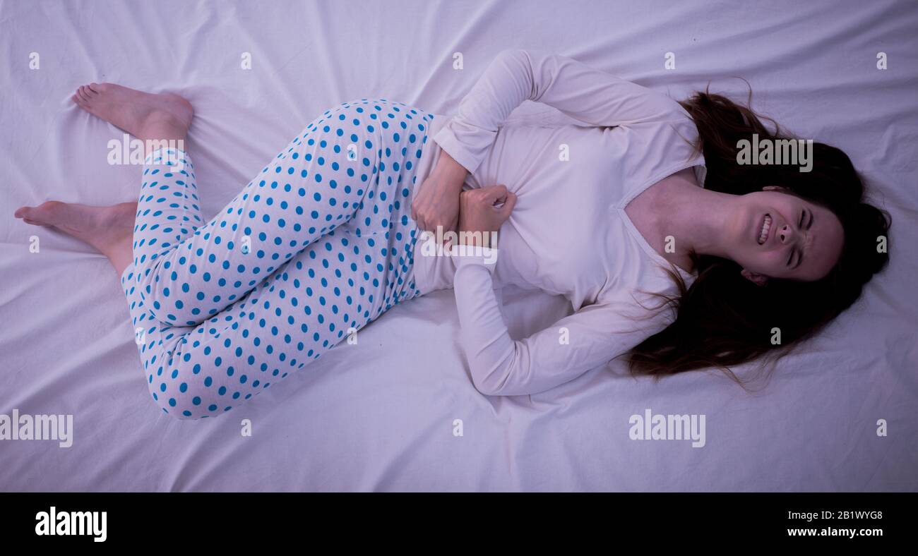 Junge brünette kaukasische Frau weh Schmerzen in ihrem Magenmenstruationszyklus Stockfoto