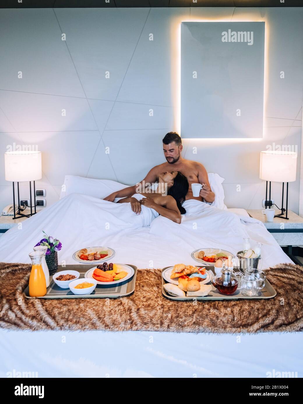 Ein Paar frühstücken im Bett, Männer und Frauen im Luxuszimmer und ein  weißes Bett mit Frühstück im Bett Stockfotografie - Alamy