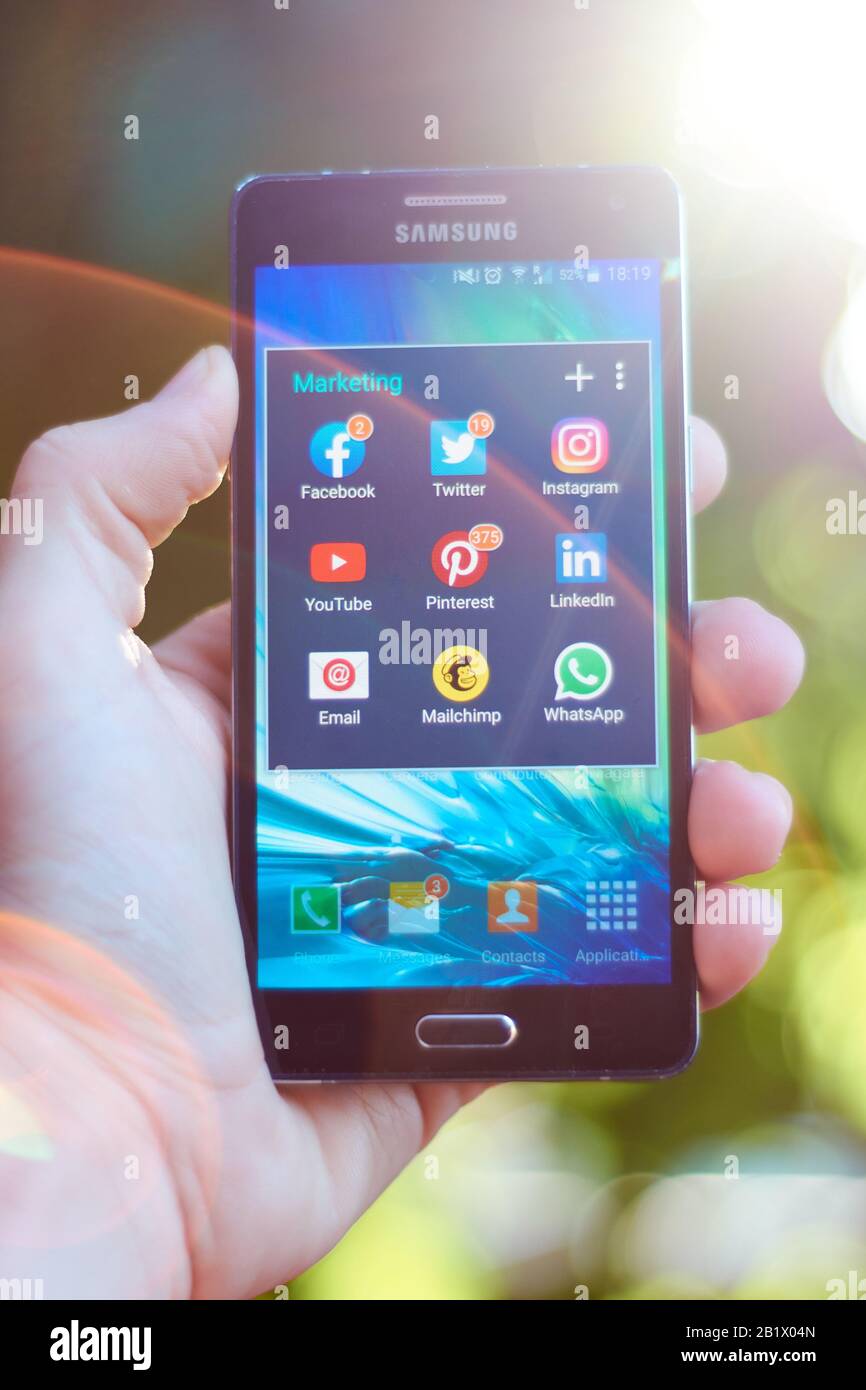 Februar 2020 - BUENOS AIRES, ARGENTINIEN: Vertikaler Handschuss mit einem Handy, das eine Gruppe von Marketing-Apps in einem virtuellen Ordner mit Unschärfe zeigt Stockfoto