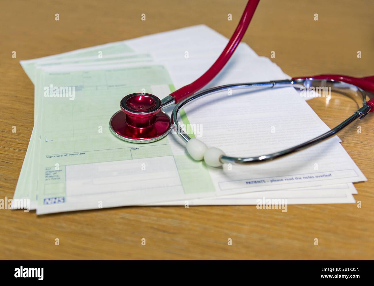 Ein Stapel leerer NHS-Rezepte und ein rotes Stethoskop in einer Arztpraxis Stockfoto