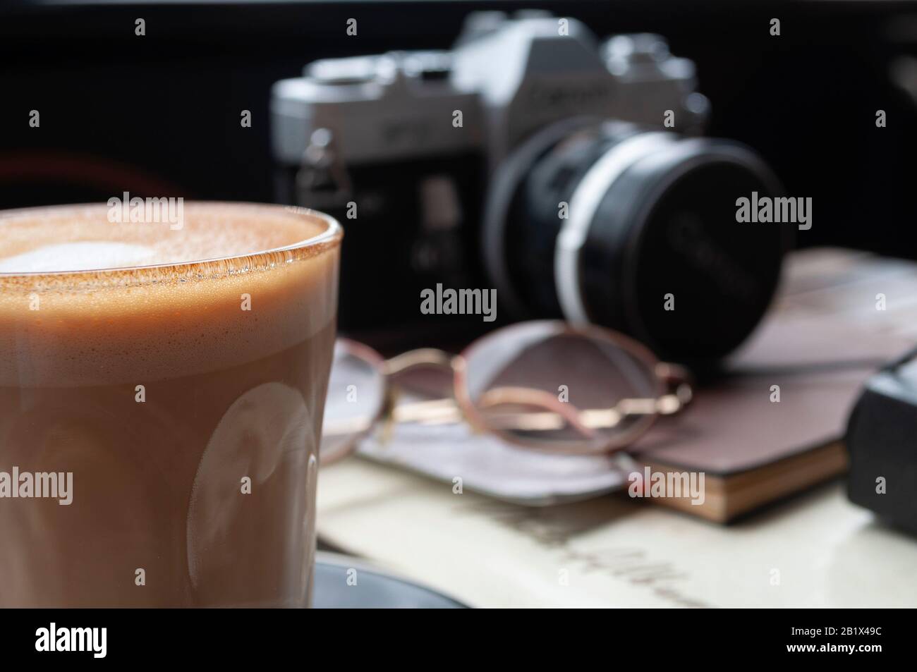 Latte mit Vintage-Kamera und Brille im Hintergrund Stockfoto