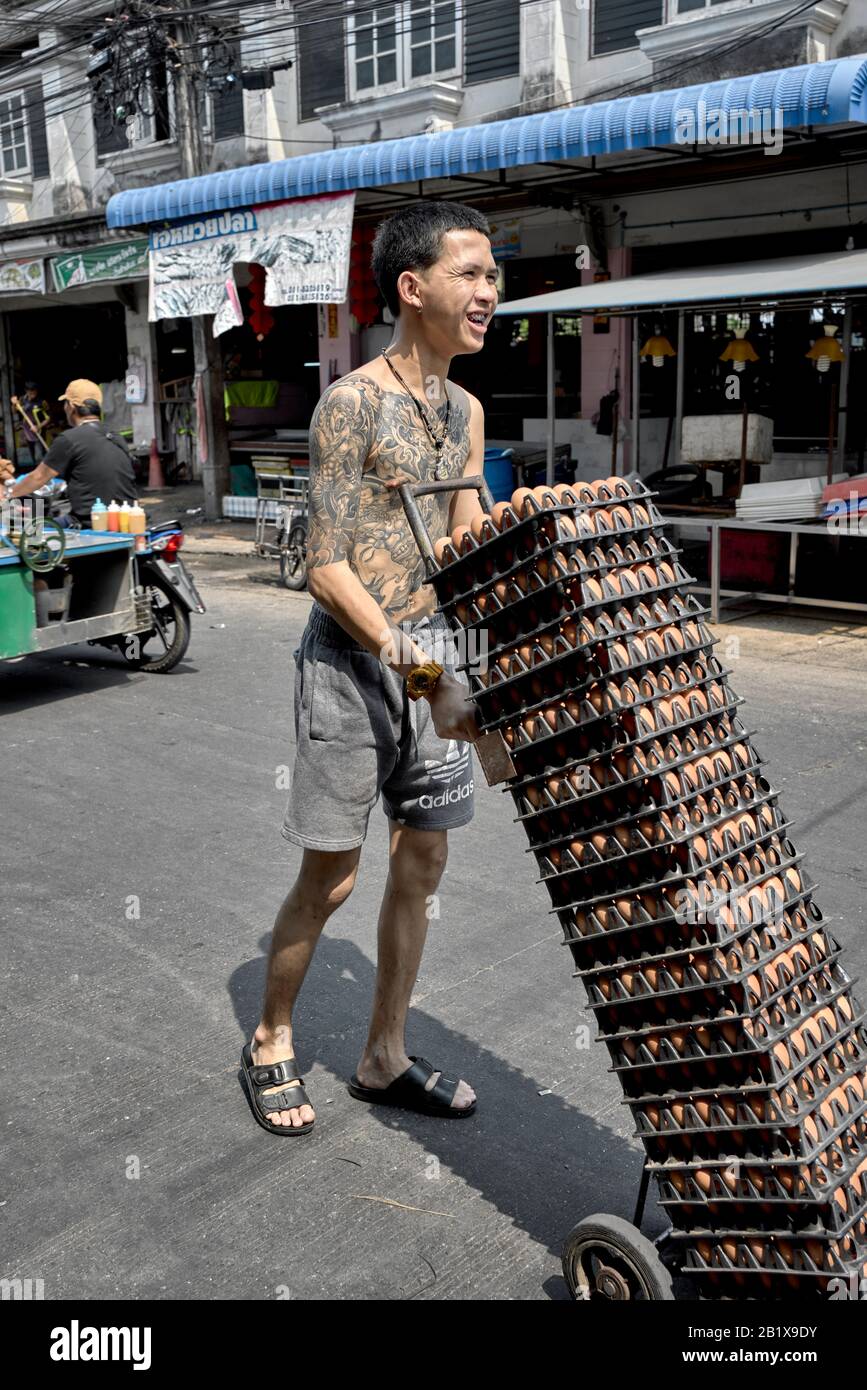 Tätowierte Männer, die Eier mit einem Handwagen transportieren. Thailand Street Szene Stockfoto