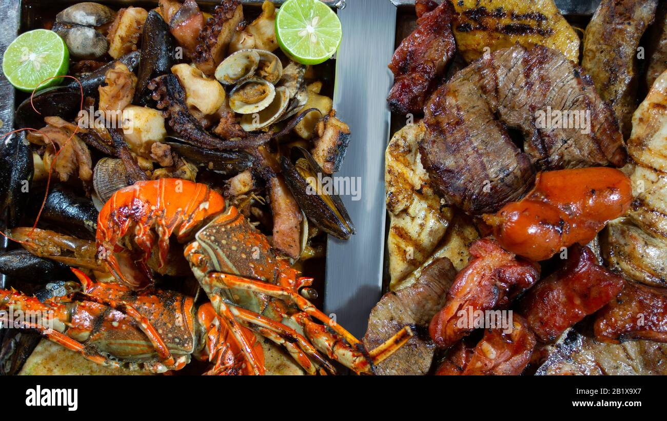 Blick auf gegrilltes Fleisch mit Würstchen und Meeresfrüchtegrill mit Hummer, Garnelen, Schale, mit Zitrone begleiteten Muscheln Stockfoto
