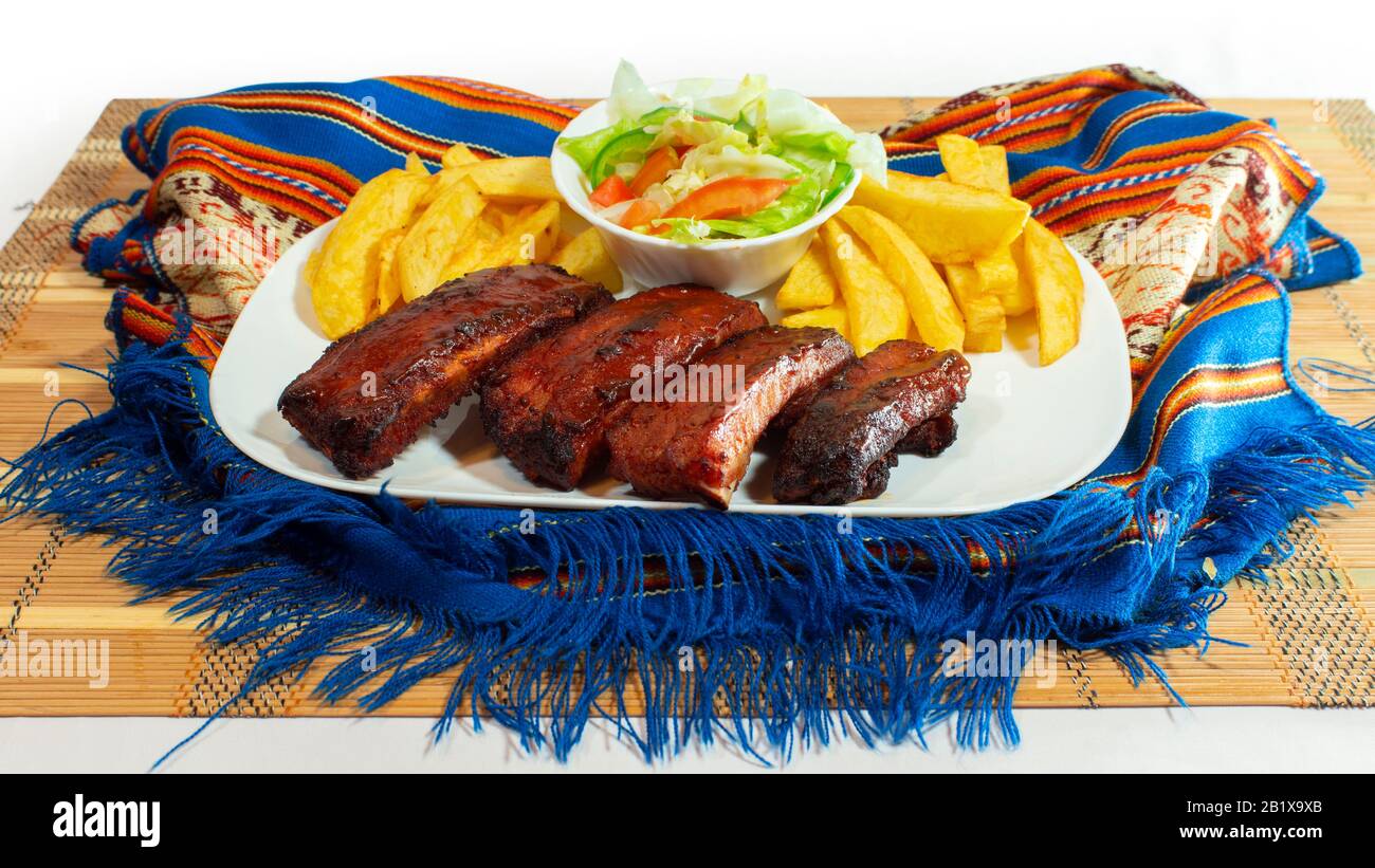 Platte mit Grillrippen, begleitet von pommes frites und Tomaten- und Salatsalat auf weißem Hintergrund Stockfoto