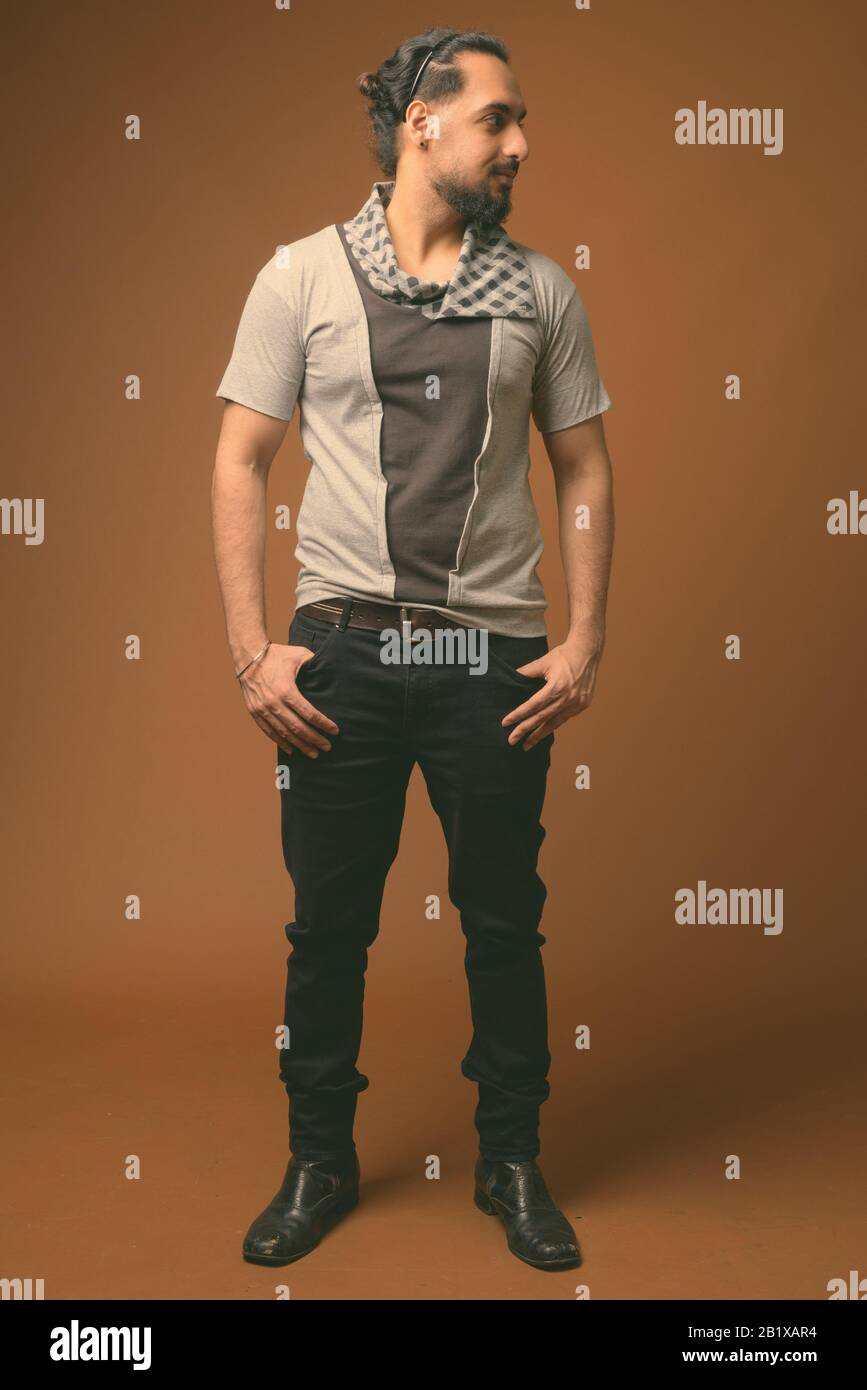 Studio erschossen Der junge Bartgeier indischen Mann, stilvolle Kleidung gegen braunen Hintergrund Stockfoto