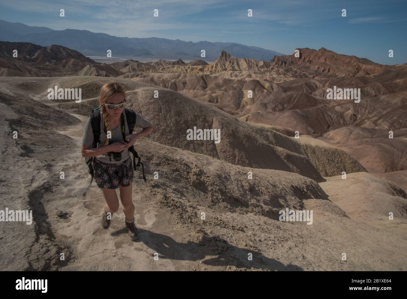 Ein weiblicher Wanderer geht einen Weg durch die Hügel und die Wüste im Tod Valley National Park in Kalifornien. Stockfoto