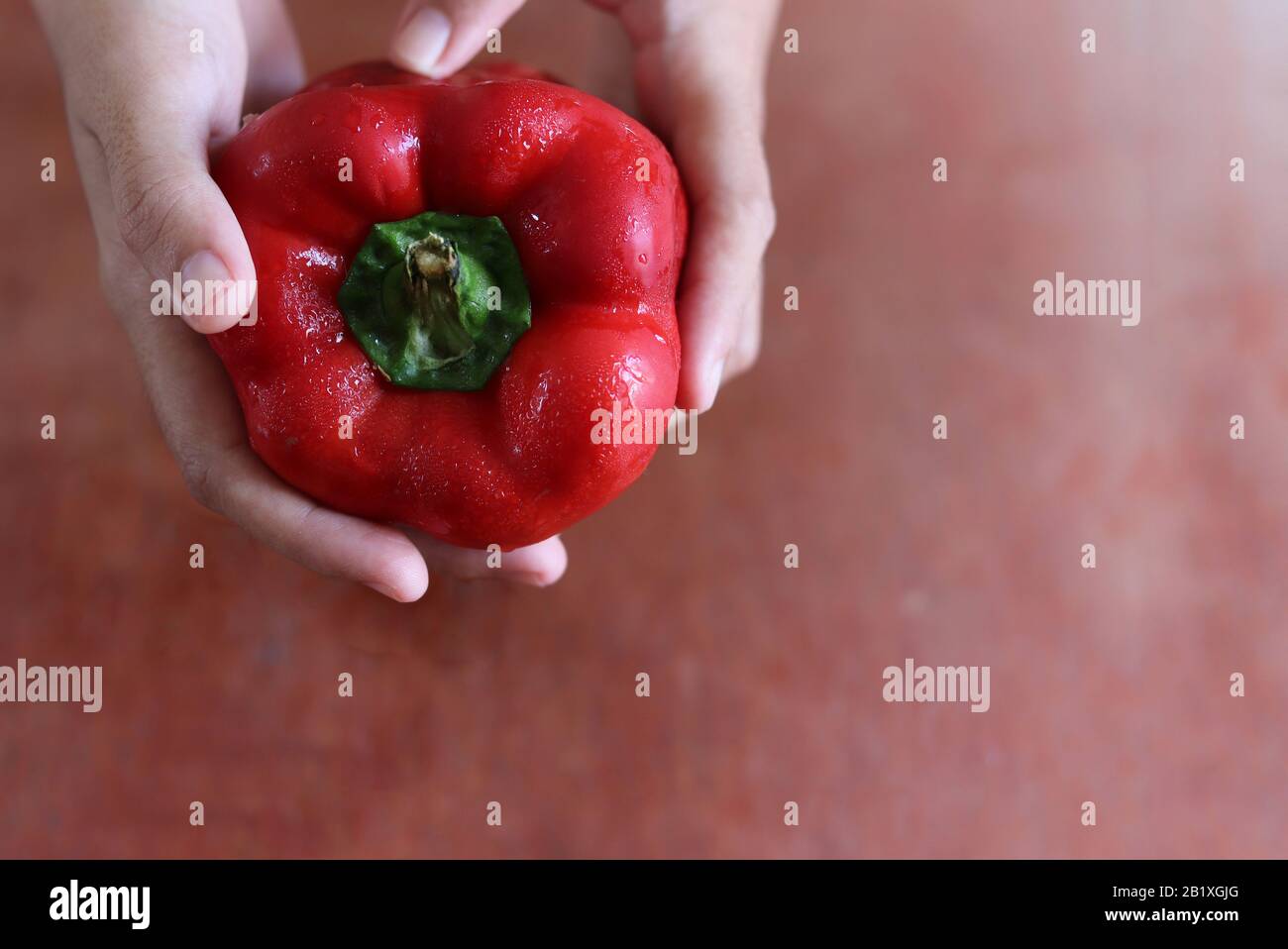 Konzeptionelles Foto einer Hand, die einen roten Paprika hält, um die Bedeutung einer gesunden Ernährung in Zeiten der Hausquarantäne, Selbstisolierung und zu zeigen Stockfoto