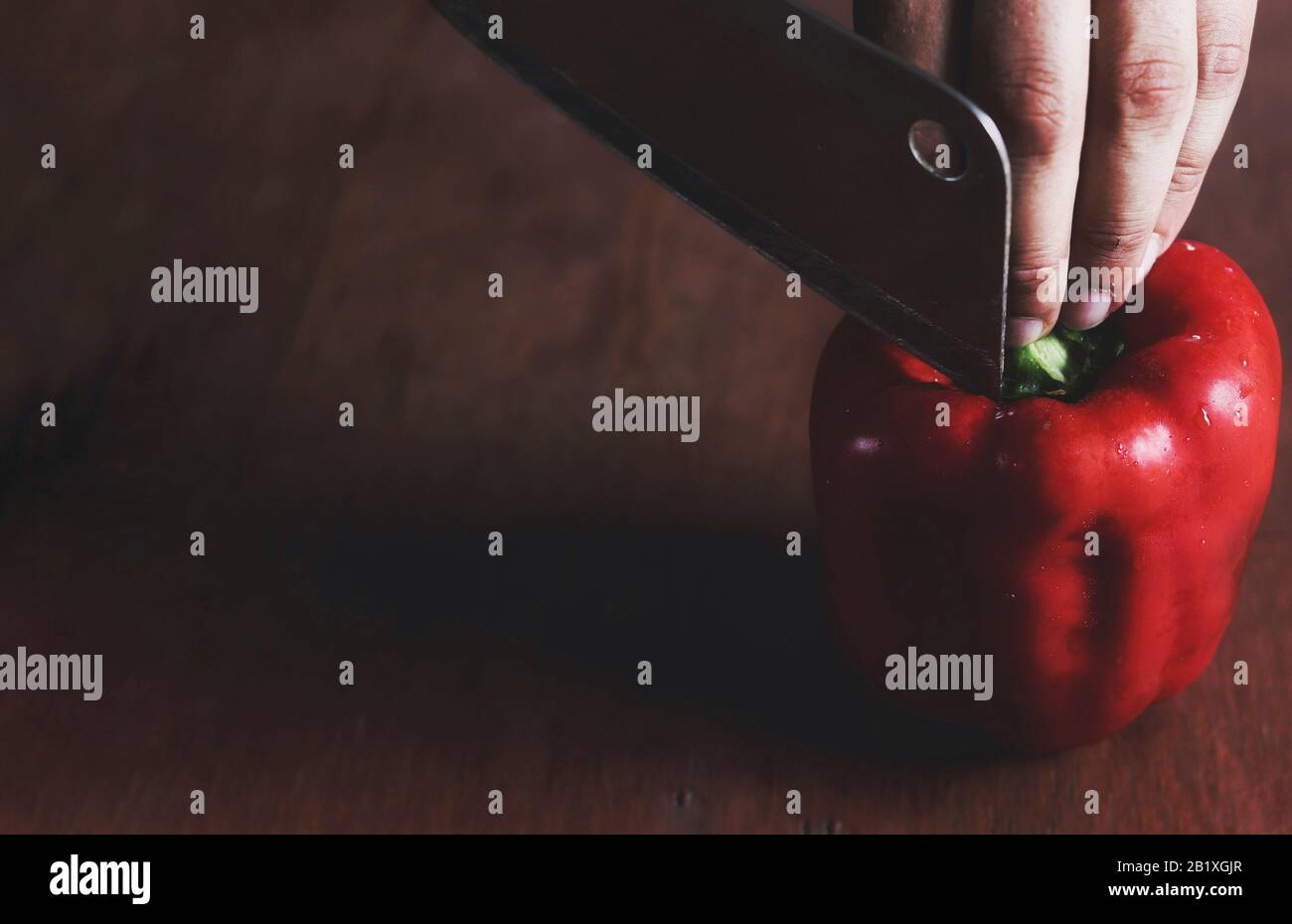 Minimalistisches Stillleben eines roten Paprika (Paprika), der in Scheiben geschnitten wird, um das Konzept der Küche, Küche, Gastronomie und der Lebensmittelindustrie zu zeigen Stockfoto