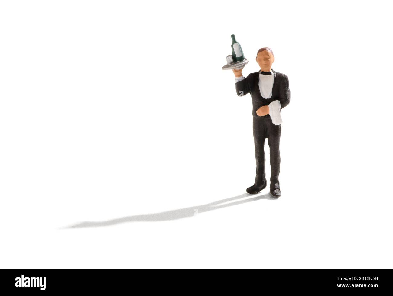 Kellner mit einer Flasche Wein auf dem Tablett in einem Tuxedo in einem Nachtclub oder Hotel über einem weißen Hintergrund Stockfoto