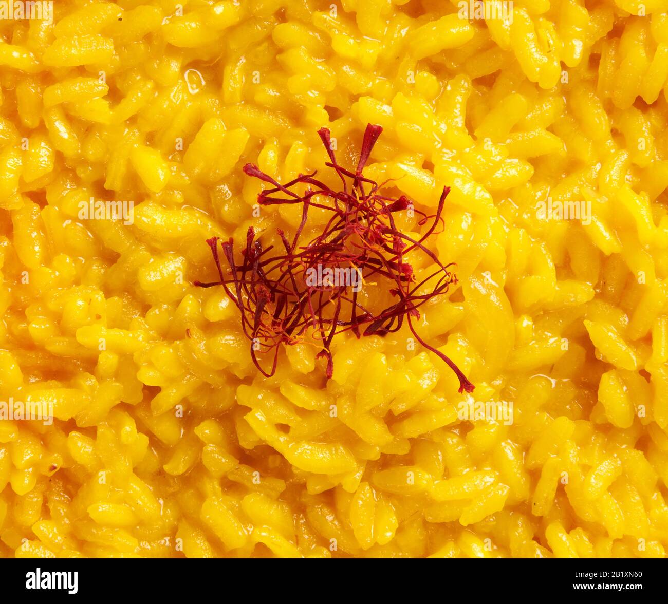 Vollformattextur aus cremig gelbem italienischen Risotto Reis, garniert mit Safranpistillen oder Fäden, einem luxuriösen Gewürz, aus der Region Lombardei in Italien Stockfoto