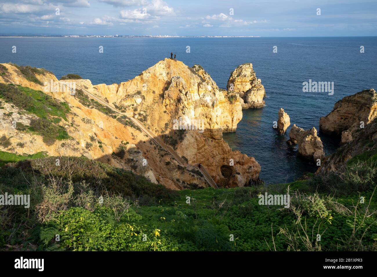 Lagos, Portugal - 22. Januar 2020: Thrillseeker Touristen machen Fotos mit einem Telefon auf einer sehr steilen Felswand an der Algarve, mit malerischen Aussichten Stockfoto