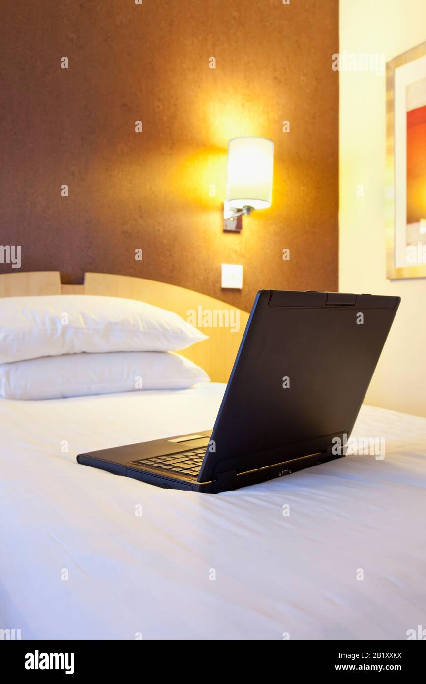 Laptop in einem Hotelzimmerbett nachts Stockfoto