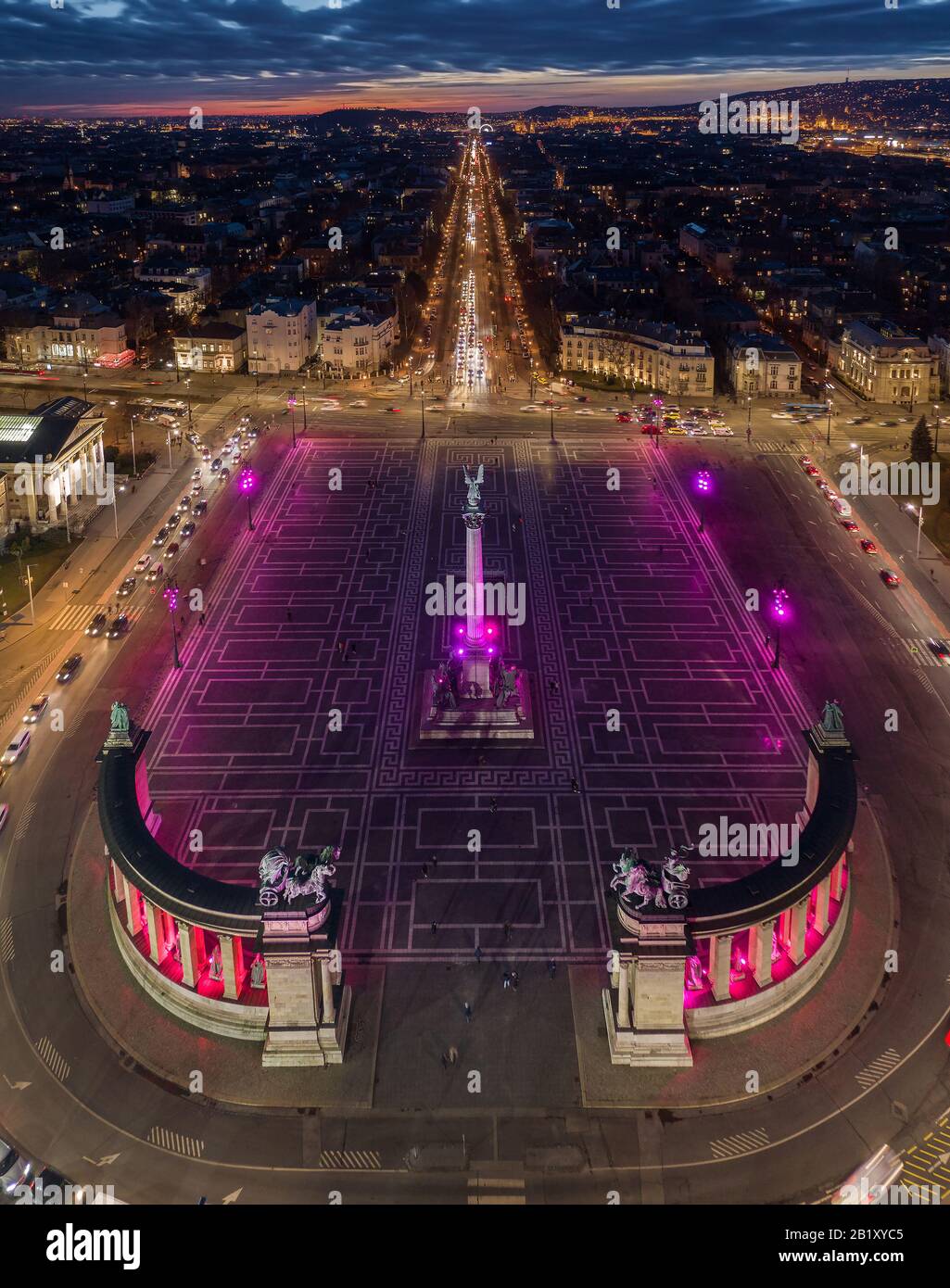 Budapest, Ungarn - Luftdrone Blick auf den berühmten Heldenplatz (Hosok tere) leuchtet nachts in der einzigartigen violetten und rosafarbenen Farbe mit Andrassy Straße A Stockfoto