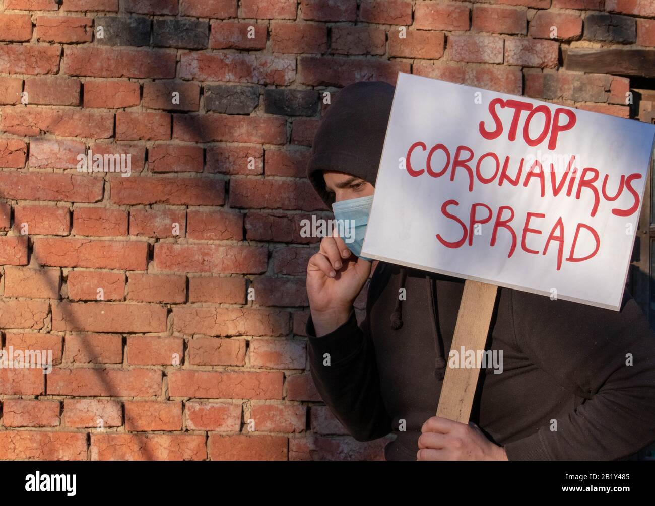 Mann mit Banner Stop Coronavirus Verbreitet. Der Mann protestiert und fordert Regierungen auf, bei der Bekämpfung des Corona-Virus zu helfen. Person ermutigen Wissenschaftler, die Pandemie zu stoppen. P Stockfoto