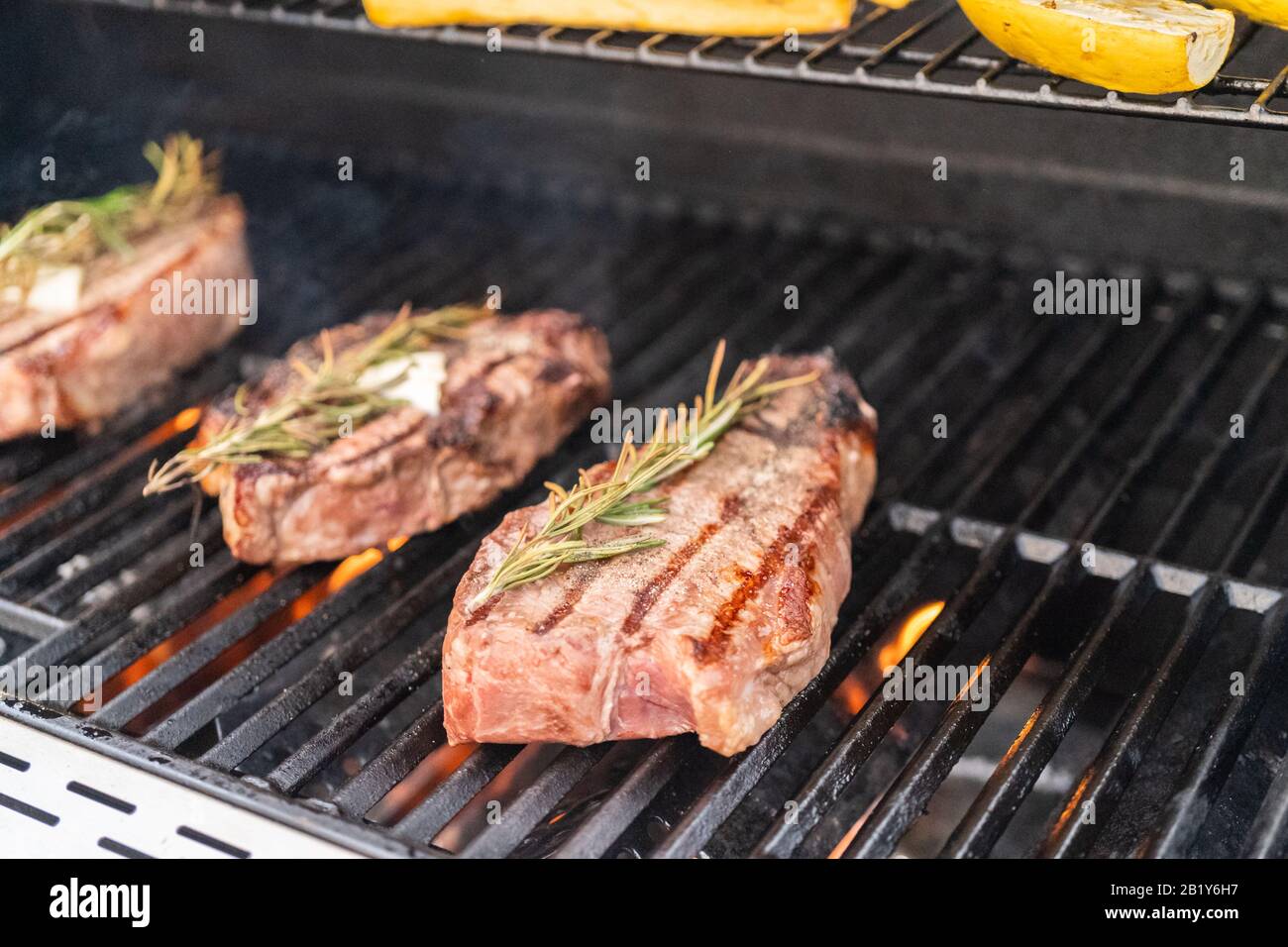 Grillen New York Steak mit einem Stück Butter und Rosmarin auf einen  Outdoor Gas Grill Stockfotografie - Alamy