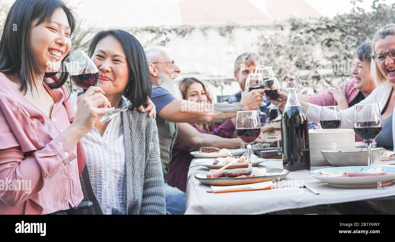 Fröhliche Familienfreunde essen und trinken Wein beim Barbecue-Dinner auf der Terrasse im Freien - Reife und junge Leute haben Spaß am bbq-sonntagmenü - Essen und e Stockfoto