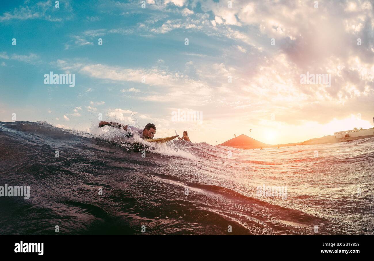 Surfer, der beginnt, eine Welle bei Sonnenuntergang zu fahren - Man surfin im Freien im Ozean - Extreme Sport- und Urlaubskonzept - Konzentriert sich auf männlichen Körper Stockfoto