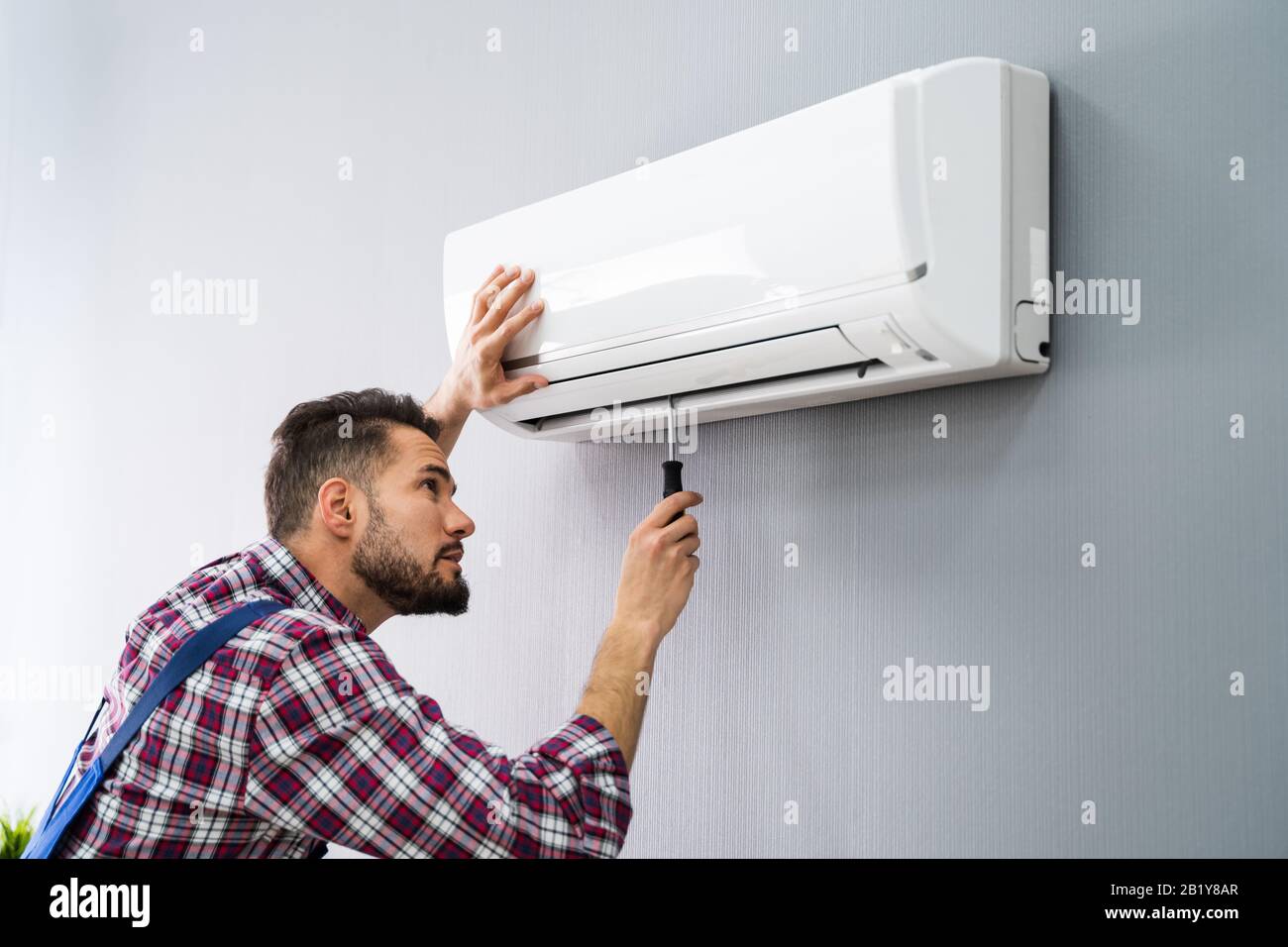 Happy männlichen Techniker Reparatur Klimaanlage mit Schraubendreher Stockfoto